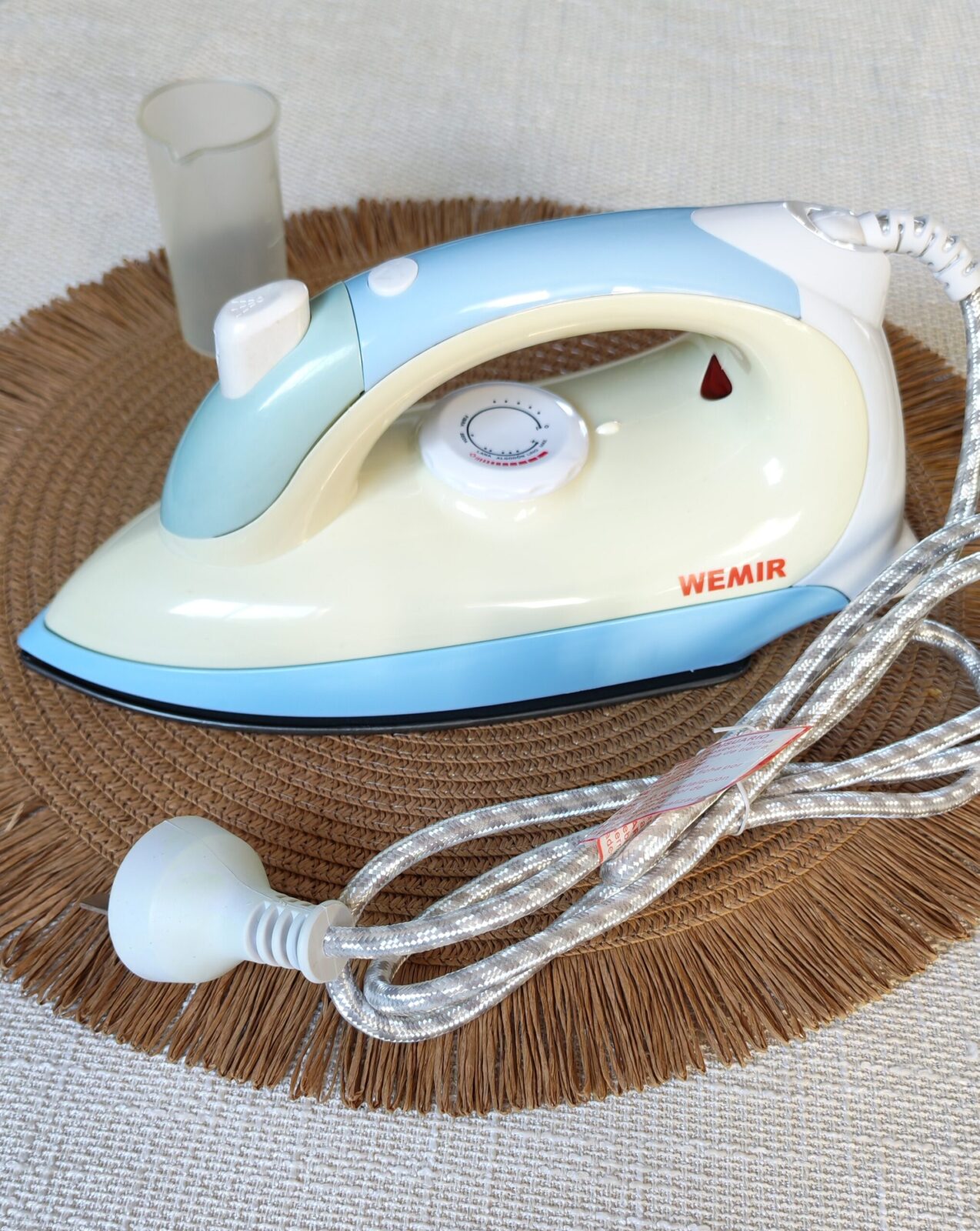 Plancha Wemir de color celeste y blanco, con una base antiadherente de 1200W y función de spray.