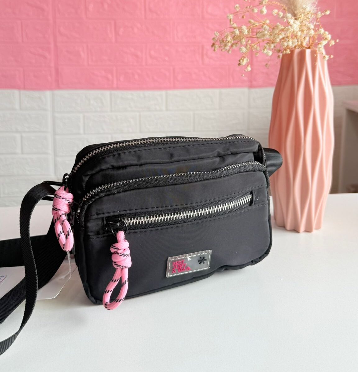 Bandolera negra con cierre en rosa